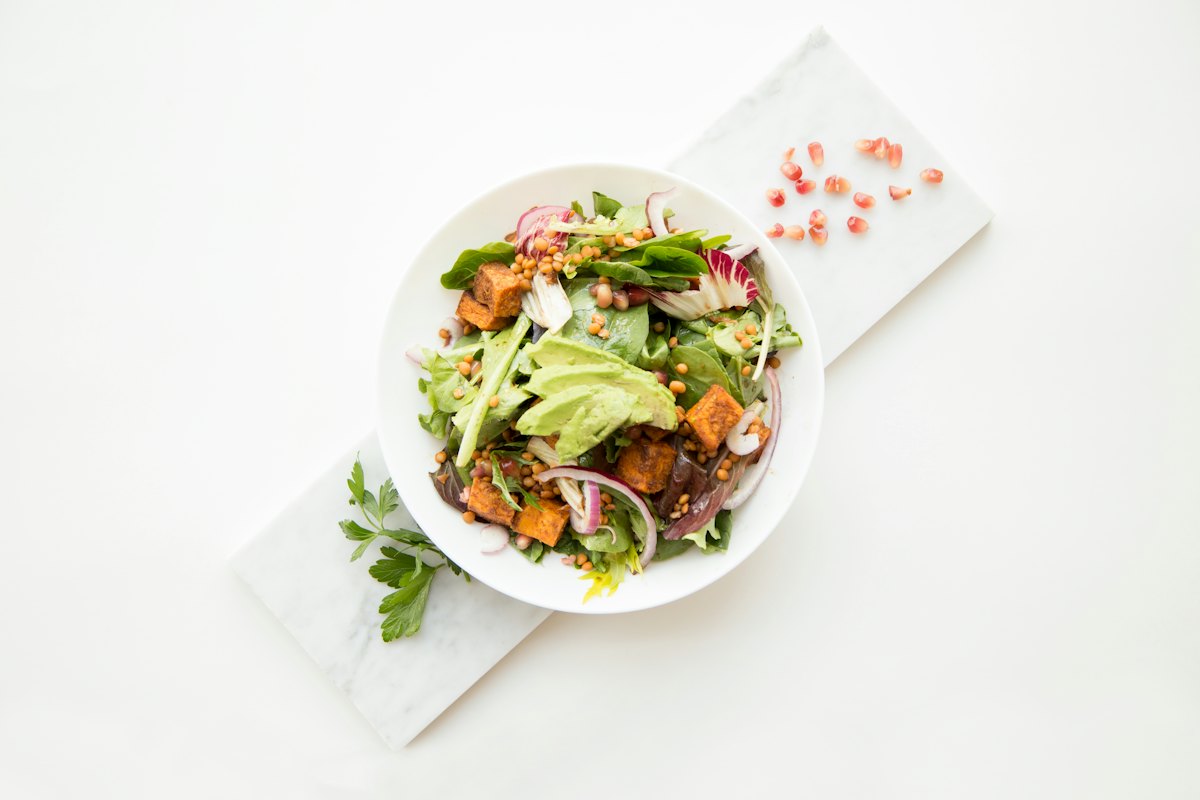 A taco bowl with greens, beans, corn and avocado
